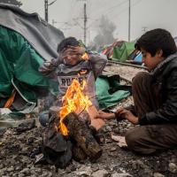 Zwei Kinder wärmen sich im griechischen Flüchtlingscamp Idomeni an einem offenen Feuer. Foto: Olmo Calvo